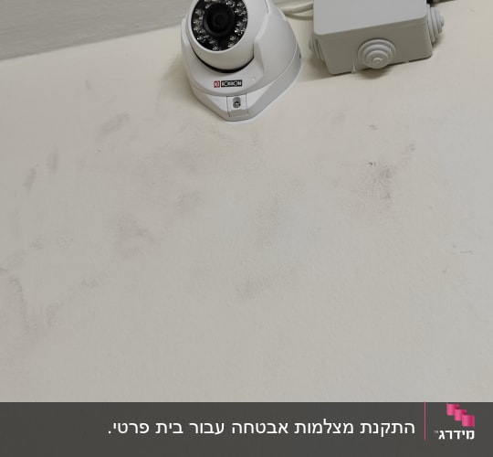 מצלמת אבטחה מותקנת על קיר לבן ליד קופסה אפורה